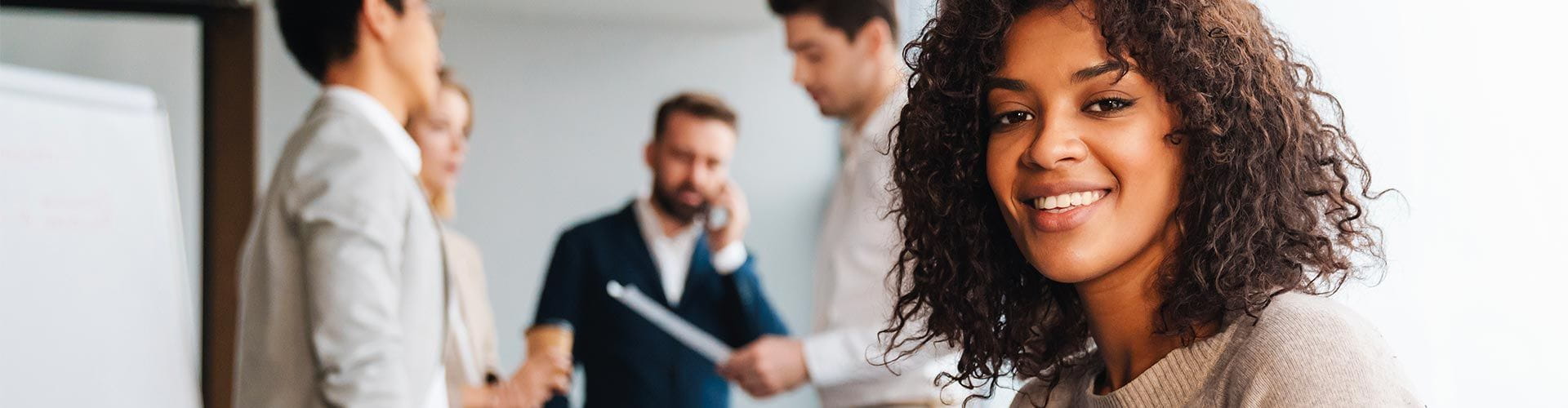 Femme souriante au premier plan et 4 personnes discutant debout lors dune réunion Femme souriante au premier plan et 4 personnes discutant debout lors dune réunion