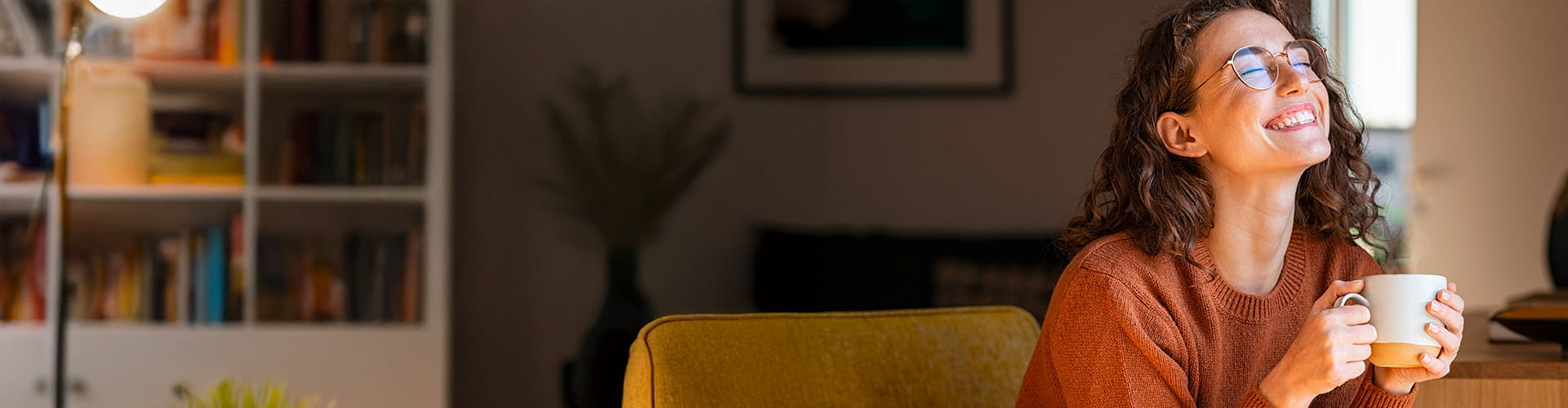 Une jeune femme souriante avec des lunettes travaille sur un ordinateur portable