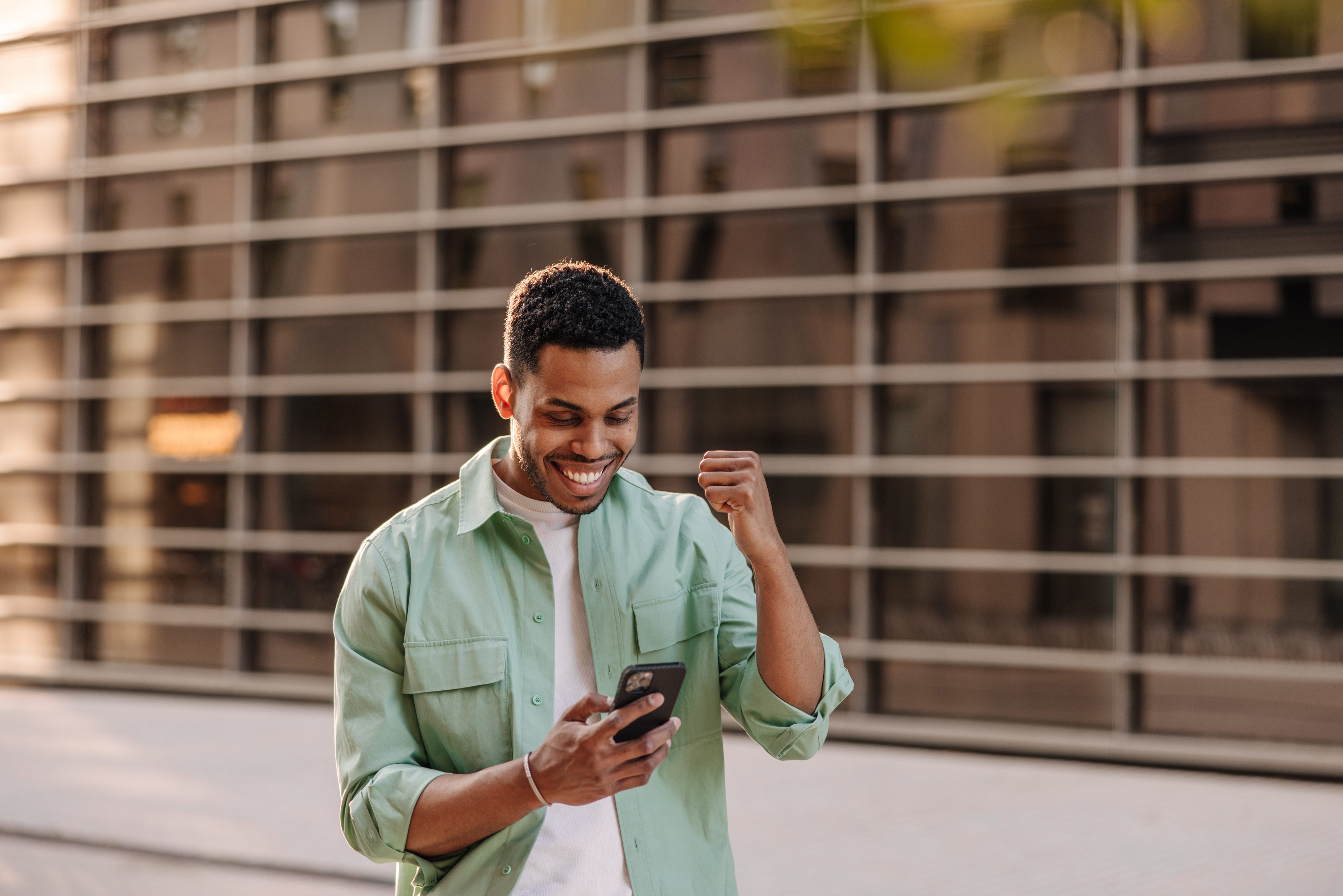 man in green shirt looking at phone doing a fist pump