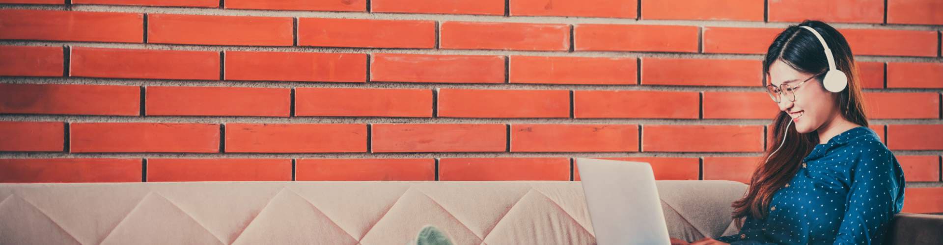 Une jeune femme souriante avec des lunettes travaille sur un ordinateur portable