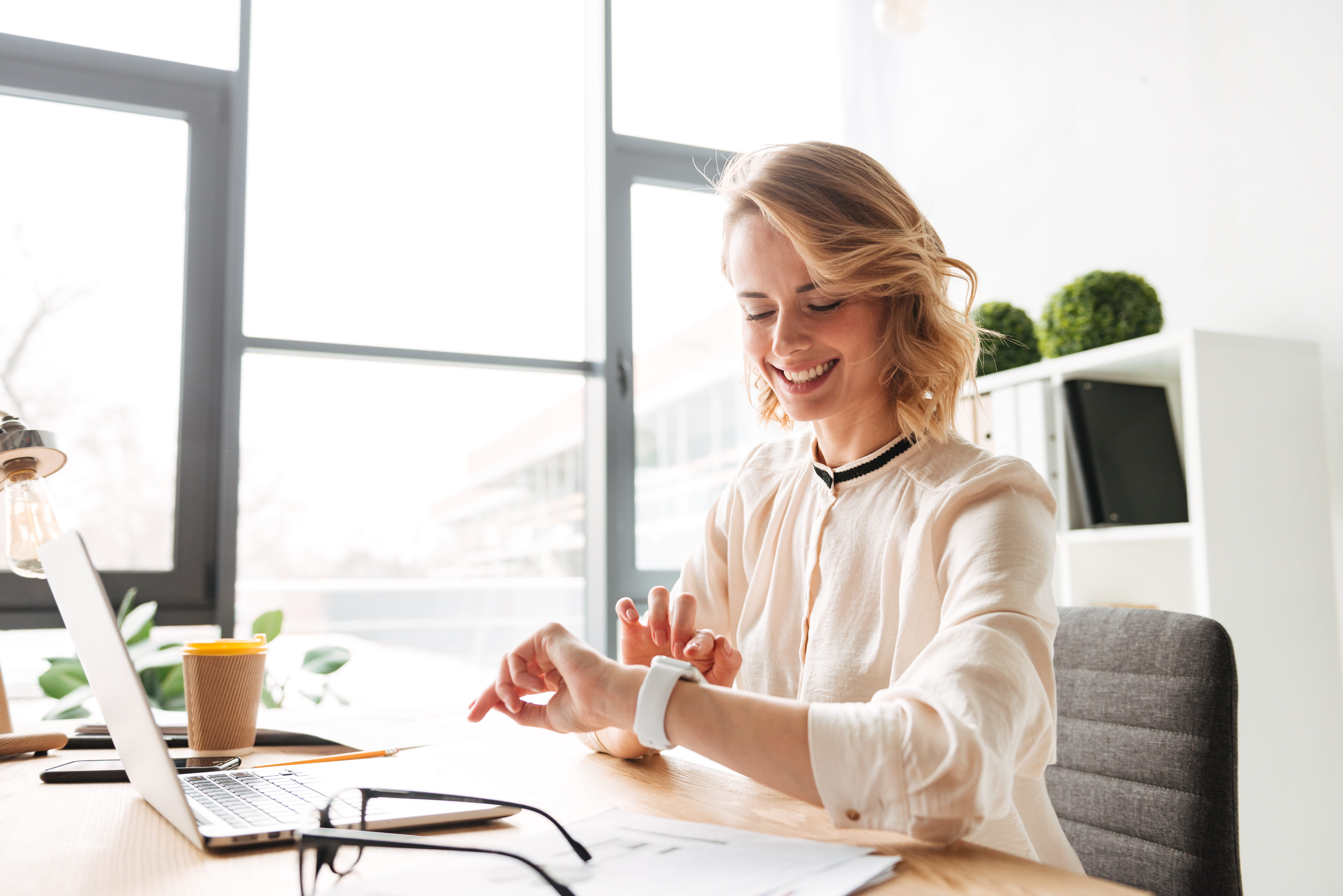 Smiling person sitting at a desk holding a notebook in colorful office. Smiling person sitting at a desk holding a notebook in colorful office.