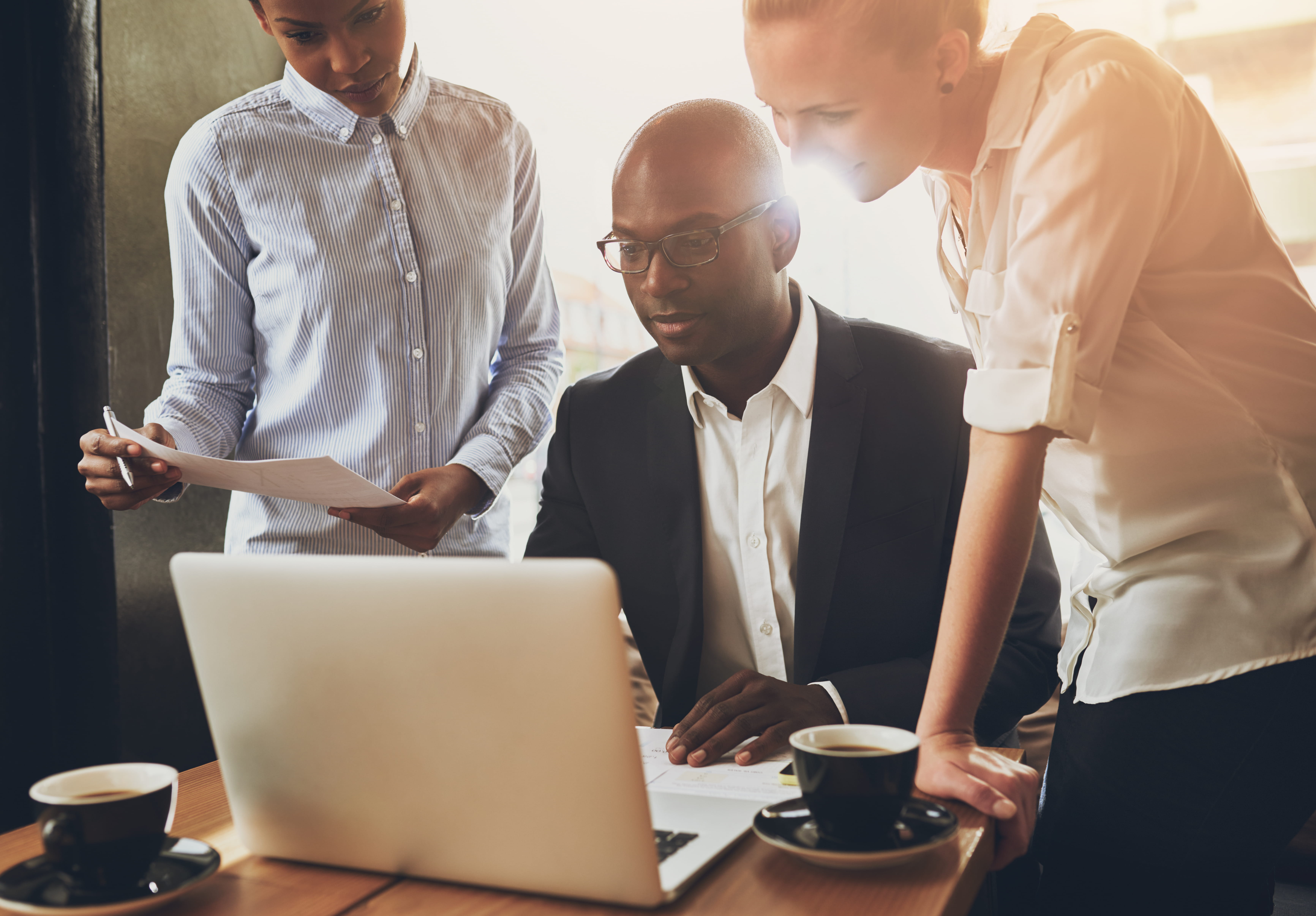three professionals looking at laptop three professionals looking at laptop