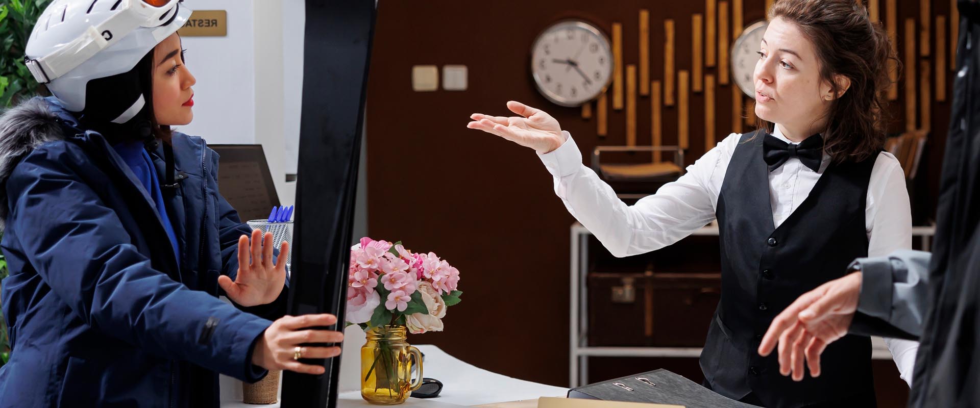 Hotel staff assisting guests at the front desk with a welcoming smile