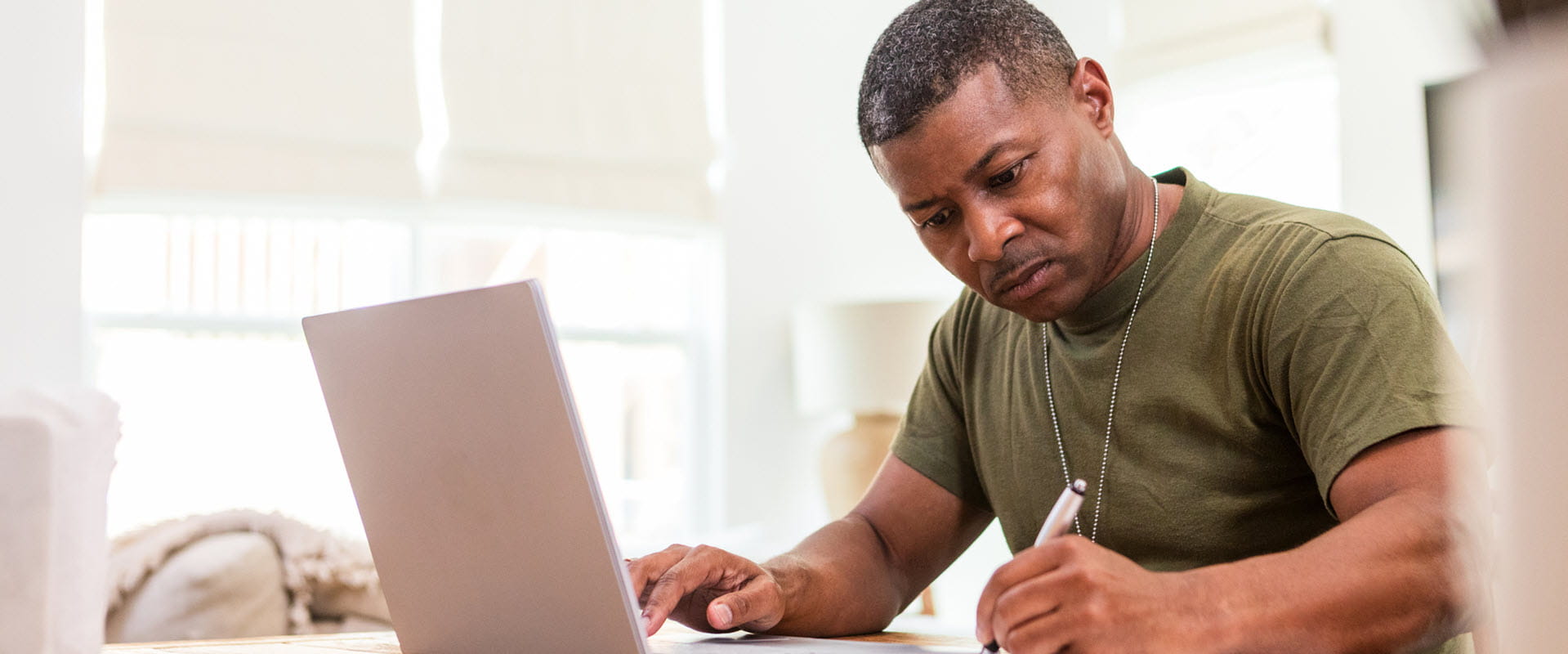 man in army tshirt working at computer