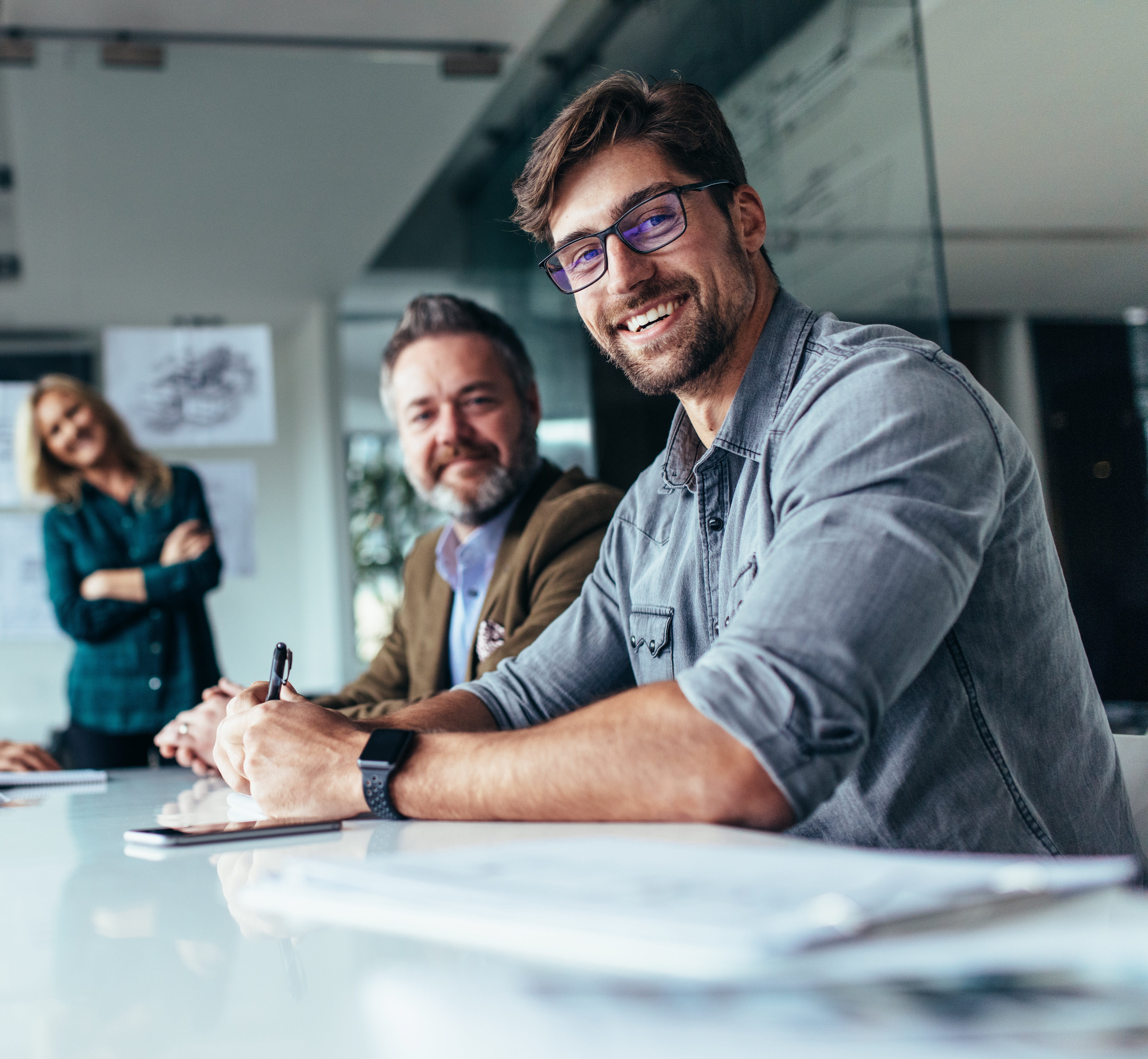 Smiling workers sitting at a conference table in an office. Smiling workers sitting at a conference table in an office.