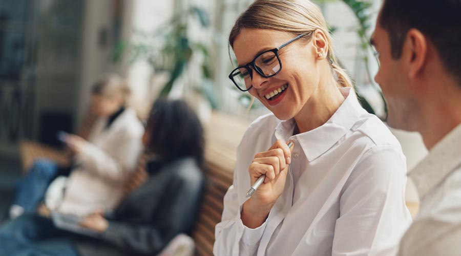 Office workers discussing project updates around a desk Office workers discussing project updates around a desk