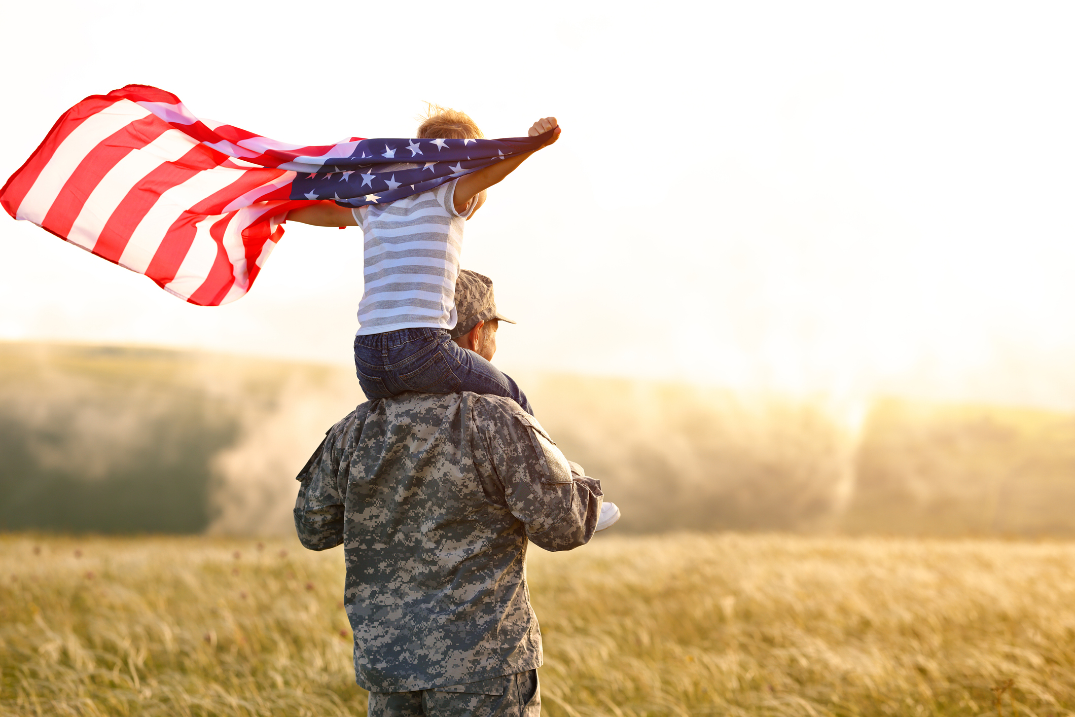 rear view of child on military man's shoulders